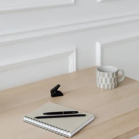 a notebook, pen and mug on a desk
