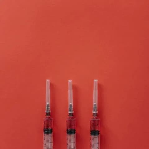 three syringes on a red surface
